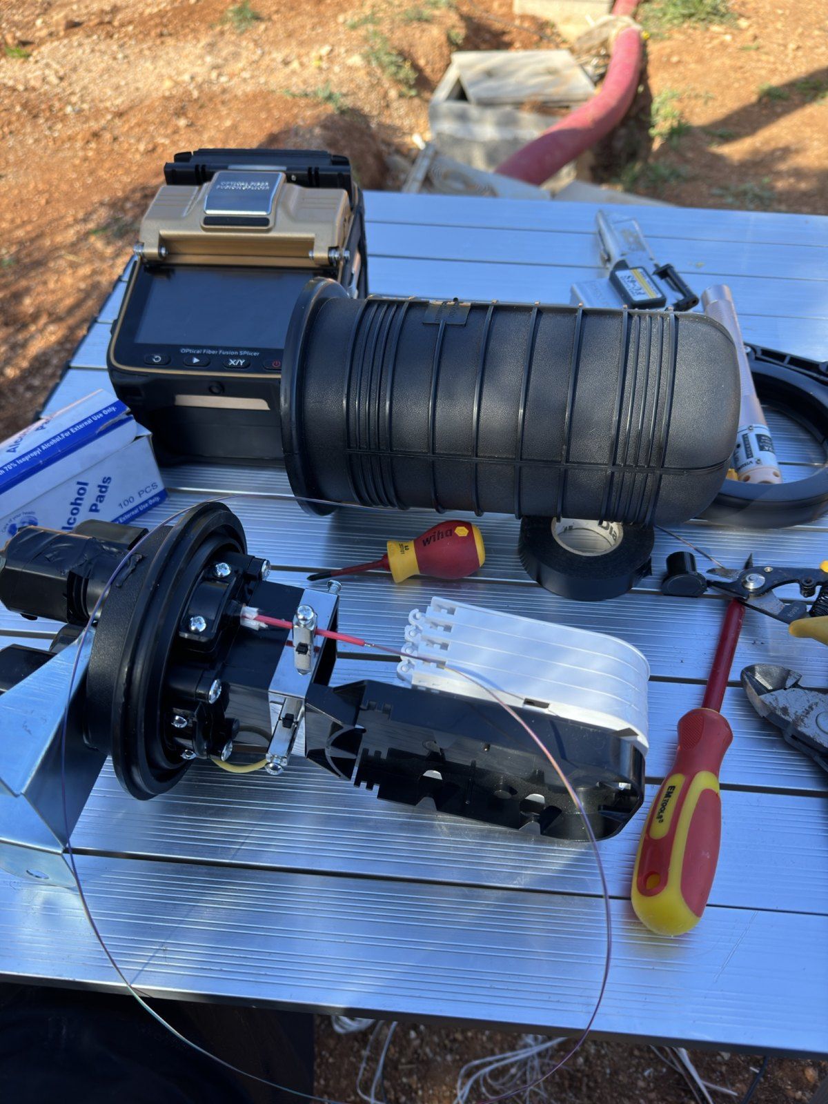 Glasfaser-Muffe und Spleißgerät auf einer Finca auf Mallorca, im Hintergrund der Kabelgraben