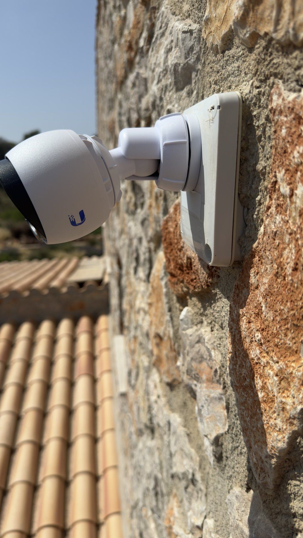 UniFi-Bullet-Kamera an einer Natursteinwand über einem Ziegeldach auf Mallorca